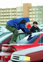 Trevor Johnson, a KU Freshman from Oconomowoc, Wis., left, puts his
entire body into his work as he chips at the ice on his car's back
window. Johnson and his friend Brent Stevens, a Wichita sophomore,
right, were clearing the windows Monday after classes.