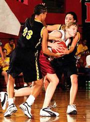 Lawrence High's Emily Schwartz, center, tries to fight her way
through a double team applied by Topeka High's Stefanie Carter,
left, and Pam Ferrero. The Trojans popped the Lions, 57-44,
Saturday night at LHS.