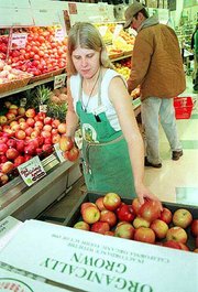 Produce assistant Bridget Meier stocks organically grown apples
Wednesday at the Community Mercantile Co-op, 901 Miss. The USDA
passed regulations that will require organic farmers to meet
certain standards to carry an "organic" label.
