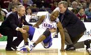 An unhappy Kenny Gregory gets helped up by Roy Williams, left, and
KU trainer Mark Cairns after Gregory was decked by a KSU player.