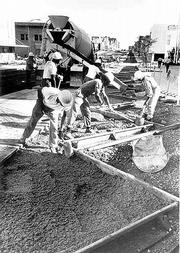 As long as there&squot;s been a downtown, there&squot;s been an issue with
parking whether it was horses, buggies or, later, cars. Workers in
the early 1970s pour concrete to form the "saw-tooth" parking
spaces that line Massachusetts Street.