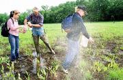 Fifth-grade students from Hillcrest school have a field trip to
learn how to apply seeds to a wetland area north of Lawrence. From
left, student Marvie Paez and volunteer and retired biology teacher
Stan Roth look through Paez's seed bag Friday while a cloud of fine
wetland plant seed is released by Crystal Miller.