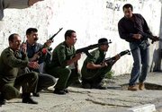 Palestinian police officers take cover after Israeli forces
rocketed their headquarters Thursday in Gaza City.