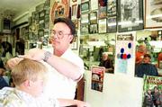 Mike Amyx, right, maintains a large display of sports memorabilia,
which adorn the walls of the Amyx Barber Shop, 842 1/2 Mass.