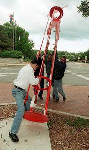 Eight new pieces of artwork are up as part of the 14th annual
Downtown Lawrence Sculpture Exhibition. Thursday near Sixth and
Massachusetts streets, Dan Sabatini, a member of the Lawrence Arts
Commission, and a trio of Lawrence Parks and Recreation workers,
from top left, Larry Colley, Kip Patzel and Mark Graves, install
"Artist Hanging On" by Omaha, Neb., artist Leslie Bruning. The
exhibit continues into spring 2002.