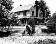 A month after the mid-July flood, A.B. Ewing shovels the dried mud
and sand that covers his once-beautiful lawn. The high-water mark
is evident on the side of his house, just under the first-floor
windows.