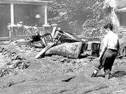 Mud to the top of her boots, an unidentified woman comes home to
wreckage, her mud-covered furniture strewn across the front lawn.
The Red Cross mobilized quickly to help flood victims. A July 17,
1951, newspaper report quoted a Red Cross official as saying that
"persons will have homes and furnishings replaced on a scale
approximating their previous standard of living."
