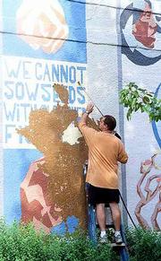 The "Seeds" mural on the east wall of the former Community
Mercantile, 9th and Mississippi and painted by Dave Lowenstein,
Sandy Broughton and friends in December of 1996, is removed from
the building. Tuesday John Patchen with Johnson Construction,
Lawrence, power washes paint off the building which will be the
location for a new Cork and Barrel Wine and Spirits store. Several
neighbors and passersby were upset to see the colorful mural being
removed.