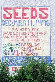 A mural project completed in December 1996 decorates the east wall
of the former Community Mercantile at Ninth and Mississippi
streets. A Cork and Barrel store is moving into the building and
workers began removing the mural Tuesday.