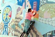 In this file photo from October, 1996, artist Sandy Broughton
paints in a scene on the "Seeds" mural on the east wall of the
former Community Mercantile at 9th and Mississippi. Tuesday workers
began removing a part of the mural with a power washer and
Wednesday the mural is to be painted over. Cork and Barrel is
opening a store in the building.