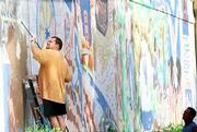 The "Seeds" mural on the east wall of the former Community
Mercantile, which was painted by muralist David Loewenstein and
others in December 1996, is ticketed for removal. Tuesday, John
Patchen, left, and Mike Atwell, both with Johnson Construction,
Lawrence, power-washed dirt and loose paint off the building at
Ninth and Mississippi streets, which will become a new Cork and
Barrel liquor store. Several neighbors and passersby were upset to
see the colorful mural being removed.