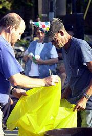 Brent Lamb, left, father of Emily Lamb, who organizes birthday
parties for the Lawrence homeless, helps Eugene Coffelt take out
the trash during a barbecue party at the Community Drop In Center,
214 W. 10th St. The center tied the celebration of Emily's 12th
birthday Thursday with a community party, offering free food and
music to the public.