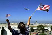 Rebecca Arellano of Hawthorne, Calif., waves a pair of American
flags from an overlook in El Segundo, Calif., as a jetliner takes
off from Los Angeles International Airport. It was the first plane
to leave the airport Thursday.