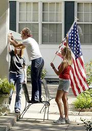 Area stores are running out of flags as many people are flying them
in response to Tuesday&squot;s terrorist attacks. Thursday at Kansas
University&squot;s Kappa Delta house, sorority sisters, from left, Liz
Telschow, Lindsey Goward and Darcie Nachbar, mount a bracket for a
new flag outside the house entrance. Nachbar was at the store
Thursday when she saw an employee unwrapping a flag and said, "I&squot;ll
take that."