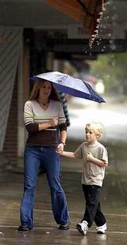 Despite having an umbrella, Tracie Mann, left, and Dante Colombo,
6, sidestep an awning's runoff to escape the rain. Lawrence
received 0.49 inch of rain from midnight Monday through Tuesday
evening, bringing the year's total precipitation to 35.40 inches.
For today's weather, please see 10B.