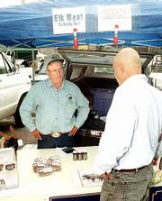 Rocky Hills Elk Ranch owner Charles Edmonds, left, talks about his
elk herd with customer Bob Anderson, Towanda. Edmonds packs his
pickup truck full of coolers containing ground elk, elk burgers,
elk steak and elk sausage each Saturday and makes the 24-mile
journey to the Lawrence Farmers Market.