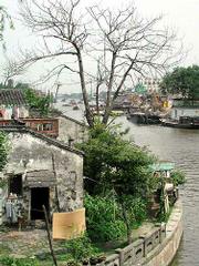 The original town of Suzhou is surrounded by a moat and
crisscrossed by canals like the one at left. Many residents have a
street running in front of their house and water flowing behind it.
In the last decade the city established two large development zones
beyond the moat. Below, the Pueschels and some students toured
commercial Nanging Road in Shanghai one night. The Pueschels were
the only westerners among perhaps 200,000 Chinese. No police were
present in the area because there is evidently no need.