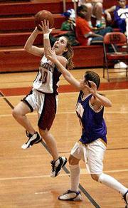 Lawrence High guard Leigh Debiasse drives past Kansas City Harmon's
Jenessa Frank for a layin on Tuesday at LHS. The Lions won the
girls basketball contest, 78-18.
