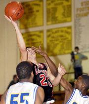 Lawrence High's StePHen Vinson stretches for a shot over Kansas
City Center's Terance Williams, left, and Odis Smith. Vinson scored
11 points in the Lions' 76-63 victory Thursday in the Blue Valley
Shootout.