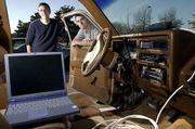 Kansas University graduate students Matt Dunbar, left, and Brett
Becker have been working on a project mapping signals of wireless
computer networks around Lawrence. Using a laptop computer,
wireless network cards and an antenna, they can detect where
networks can be found outside buildings. They hope to raise
awareness about wireless networks and their potential for being
hacked into if not properly safeguarded.