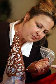 Christy Carlisle makes a chocolate lace cone by squeezing warm
chocolate ribbons onto a wax paper cone. Once the chocolate has
set, she peels the paper away from the inside of the cone.