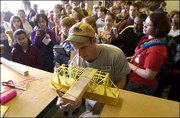 Area schoolchildren and their teachers watch eagerly as Kansas
University engineering student T.J. Huhn gauges the strength of a
bridge made of pasta. Some bridges, which were glued together, held
nearly 75 pounds. About 800 middle and high school students
registered to compete in this and other events at KU's Engineering
Expo on Friday.