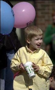 Curtis Zicker, age 5, Lawrence, clutches a Free State balloon and a
cup he received from a passing float as he cheers for an upcoming
entry.