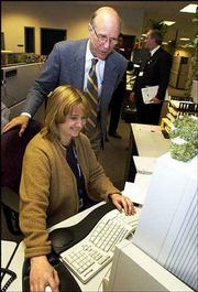 U.S. Sen. Pat Roberts, R-Kan., talks with Cheryl Blackford, a call
center supervisor at NCS Pearson, while touring the complex in
Lawrence's East Hills Business Park. Roberts praised the center
Friday for its efforts to expand employment.
