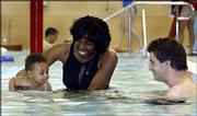 Charlene and Justin Palmer watch as their son, Wesley, 6 months,
gets his first-ever taste of swimming at the Lawrence Indoor
Aquatic Center's children's pool. The family went to the center
Sunday afternoon to take advantage of the Mother's Day family
special.