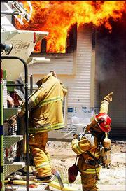 As one firefighter climbs a ladder truck, protecting himself from
the intense heat by pulling his coat over his head, another gives
instructions about how to tackle the raging fire. The fire on
Stewart Avenue broke out about 1 p.m. Saturday and was not under
control until after 2 p.m.