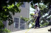 Krystal Stone, who lives south of Chase Court Apartments, hoses
down the roof of her house, which she said was covered with
smoldering pieces of ash. Stone and others sprayed water all over
their houses, roofs and yards as a precautionary step to prevent
Saturday's fire from spreading.