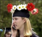 Dana Bottenfield, Lawrence, attracts attention with a
flower-festooned mortarboard. She was keeping in contact with
family members via a cell phone Sunday before she picked up her
bachelor's degree in English.
