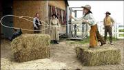 Alex Deaver, 7, of Clifton, foreground, attempts to lasso a
practice cow while his family, from left, sister Danielle, 13,
mother Judy and father Daniel, watch during some cowboy activities
at the Free State Farm in Lawrence. The Deavers, who own and
operate What Not City in Clifton, were in Lawrence Thursday meeting
with others from around the state to promote cowboy attractions to
tourists.