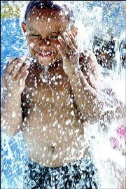 Cole Jaramillo, 5, breaks through falling water to cool off from
the weekend's high temperatures at the Memorial Park Pool in
Jefferson City, Mo. A nationwide survey has found that preteens and
adolescents dangerously downplay cancer risks from sun exposure.