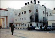 A Palestinian man walks past the compound that serves as Yasser
Arafat's headquarters. The building, the site of KU professor
Deborah Gerner's meeting with Arafat, shows fire damage on its
walls.