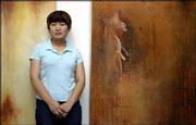 Kansas University student Mieko Ono stands by two of her paintings
on display at Fields Gallery, 712 Mass. Ono's works are influenced
by her upbringing in Japan.