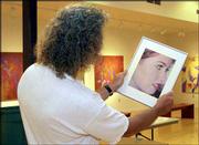 Rick Mitchell, gallery director at the Lawrence Arts Center, looks
over some of the works by Lawrence Photo Alliance members that will
be on display through Aug. 30 at the arts center.