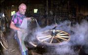 Steam rises as Don Werner sprays water onto a hot iron ring to
shrink it onto a wheel at his shop in Horton. Werner has built more
than 70 wagons that have been sold in more than 30 states.