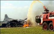 Firefighters extinguish flames from the wreckage of an SU-27 jet
that crashed into a huge crowd of spectators at an air show in
Lviv, Ukraine. The two crewmen ejected and survived, but at least
78 spectators were killed and dozens of others were injured in the
accident Saturday.