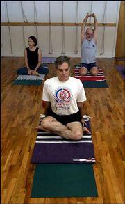 Yoga students Holly Krebs, left, Phil Schrodt, center, and Steven
Maynard-Moody stretch before class.