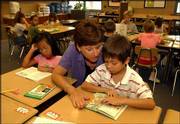 Preliminary enrollment numbers for the Lawrence school district
show a decline of 182 students, which may mean a loss of $800,000
in state aid. Enrollment was down 46 students at Schwegler School,
where Lynn Beets, a second-grade teacher, helped Nathaniel
Reynolds, 7, with some reading Monday morning.