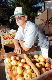 Floyd Ott, who lives south of Eudora, rests on his selection of
apples at the Lawrence Farmers Market. Ott was among the area
growers selling their goods Saturday at the market, 10th and
Vermont streets.