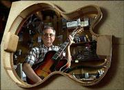 AP Photos Nelson Palen of Beloit, is seen through a template while
holding one of the archtop jazz guitars he made in his basement
workshop.