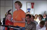 Riverside School third-grader Nick Allen adjusts the microphone for
his mother, Missy, who says the Lawrence school board should
reconsider many of the suggested changes and closings to junior
high and elementary schools in Lawrence. Allen was one of about 100
school district patrons who attended a Wednesday evening meeting
with consultants who are helping the board come up with a district
facilities master plan.