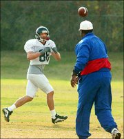 Kansas wide receivers coach tyrone Dixon, right, throws a pass to
wideout Barry Goodrich. The two worked out Tuesday on the KU
practice fields.