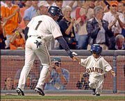 San Francisco's Kenny Lofton slaps hands with bat boy Darren Baker,
3, son of Giants manager Dusty Baker, after Lofton scored during
the NL division series against Atlanta in San Francisco. The sons
of Barry Bonds, Jeff Kent and Shawon Dunston also hang out with the
Giants players.