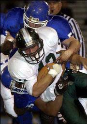 Free State's Joe Aber, foreground, drives for a few extra yards
against a pair of Washburn Rural defenders. The Firebirds rallied
for a 20-12 victory on Friday in Topeka.