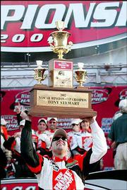 Tony Stewart hoists his championship trophy after capturing the
2002 NASCAR Winston Cup title. He sealed the victory with his
18th-place finish in the Ford 400 Sunday in Homestead, Fla.