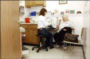 Health Care Access, which treats the uninsured and working poor, is
saving Lawrence Memorial Hospital millions of dollars, a study
shows. At left, registered nurse Betsy McCafferty works with
patient Roberta Vazquez on Tuesday at the clinic, 1920 Moodie Road.