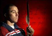 Cedric Sunray, a Choctaw Indian, is the first graduate student in
Kansas University's American Indian Linguistics program. Sunray,
who was a captain on the KU men's soccer team, hopes to preserve
his American Indian language. On Friday, he displayed a warrior
feather from the wing tips of an eagle, which is important in
Choctaw traditions and writing. Both Cherokee (top) and Choctaw
writing are pictured behind Sunray.